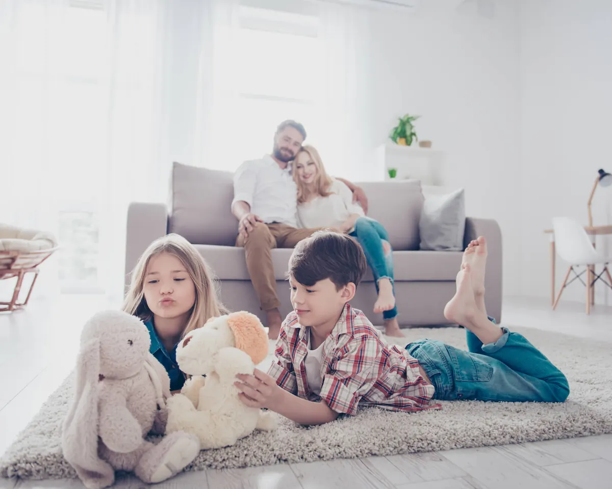 A family relaxing on a clean rug in a bright living room